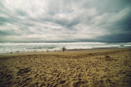 Person Carrying Surfboard While Standing on Seashore photo