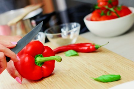 Person Slicing Red Chili Pepper on Brown Wooden Chopping Board photo