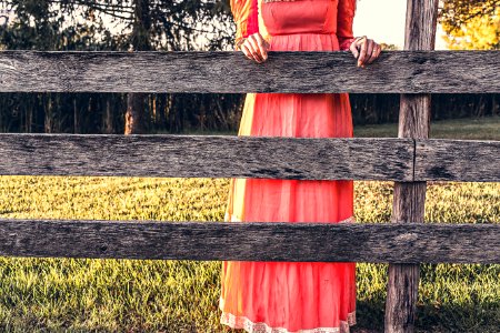 Woman Wearing Red Dress Holding Gray Wooden Fence photo