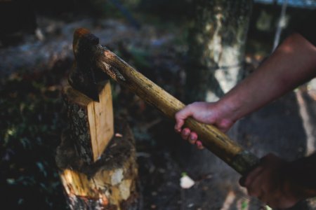 A man holds an old, worn axe photo