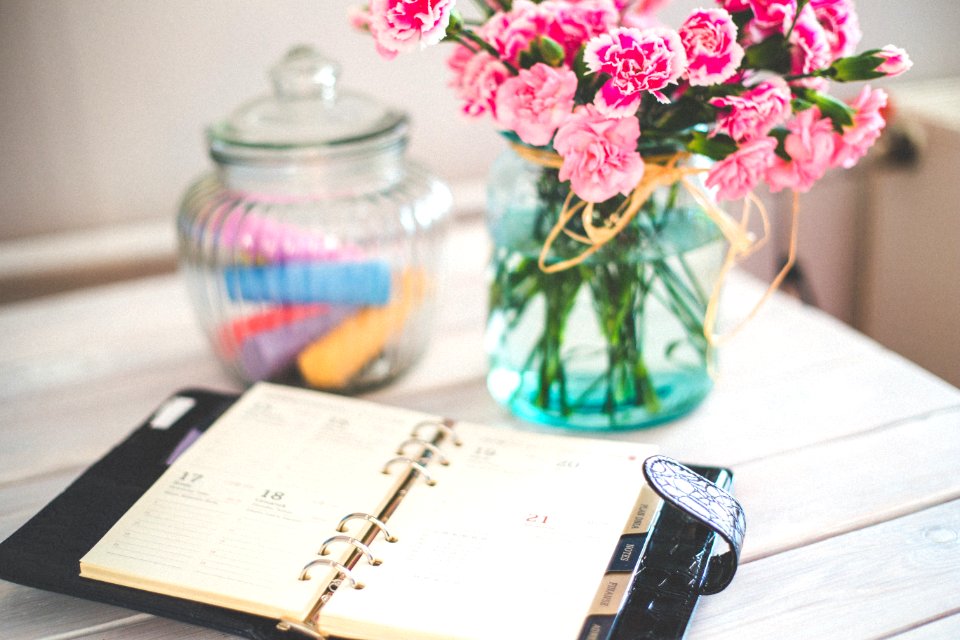 Personal organizer and pink flowers on desk photo