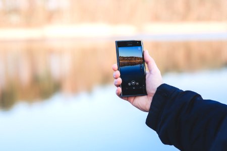 Man taking photo of a lake with mobile phone photo