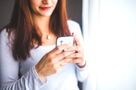 Close up portrait of a young woman typing a text message on mobile phone photo