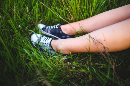 Youth sneakers on girl legs on grass photo