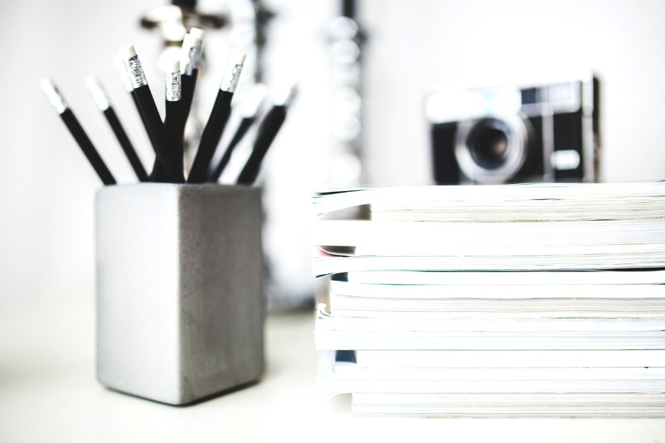 Stack of magazines & pencils in gray cup