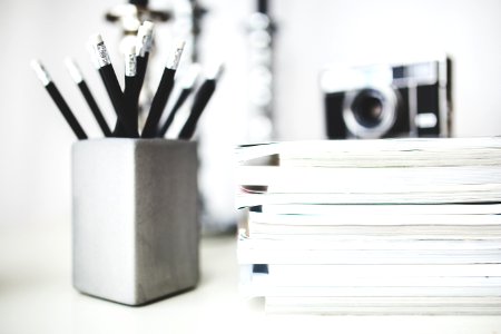 Stack of magazines & pencils in gray cup photo