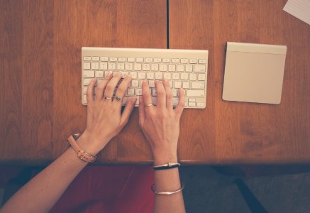 Person Using Apple Magic Keyboard on Brown Wooden Table photo