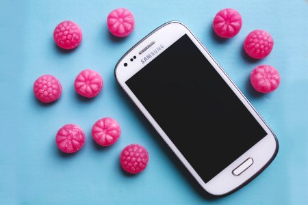Pink candies and white smartphone photo