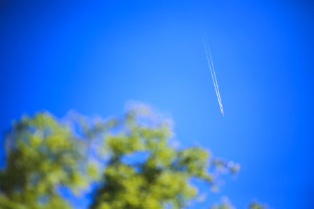 Passenger jet flying high in clear blue sky, leaving long white trail photo