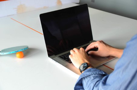 Person Hands Lying on Macbook Pro on White Table photo