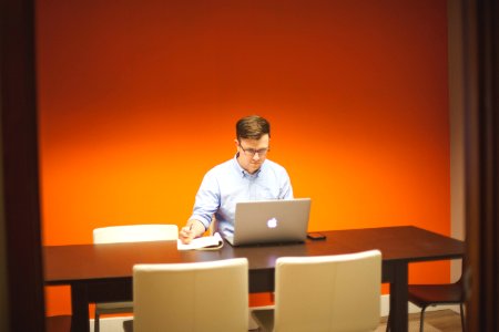 Man Using Macbook While Holding Pen photo