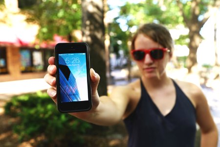 Woman Wearing Black Spaghetti Strap Top and Sunglasses Standing While Holding Space Gray Iphone 5s photo