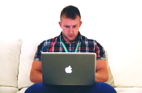 Man Using Macbook While Sitting on White Sofa photo