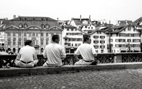 Grayscale Photography of Three Mans Sitting Near High-rise Building photo