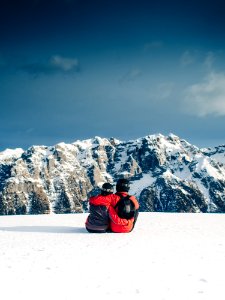 Two Person Sitting on White Snowfield photo