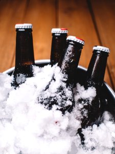 Four Beer Bottles on Gray Metal Bucket Covered With Ice photo