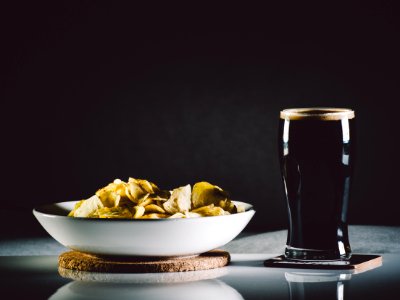 Foods in White Ceramic Bowl on Brown Coaster Next to Clear Drinking Glass Filled With Black Liquid on Coaster photo