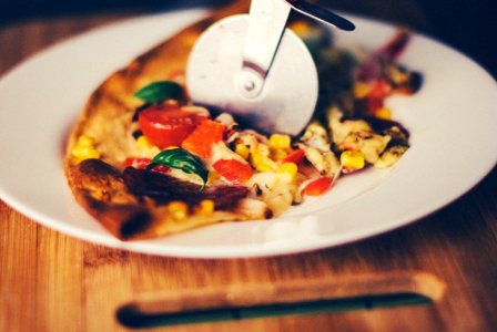 Close-up Photography of Pizza Slicer Slicing Cooked Pizza on Round White Ceramic Plate