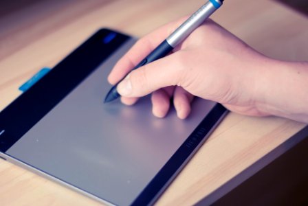 Person Holding Stylus Pen on Writing Pad photo