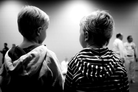 Grayscale of Two Boys Sitting Beside Each Other photo