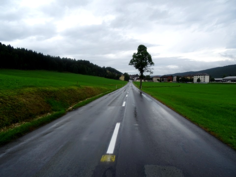 Longue ligne droite trempée, ciel bas et cycliste mouillé,… 