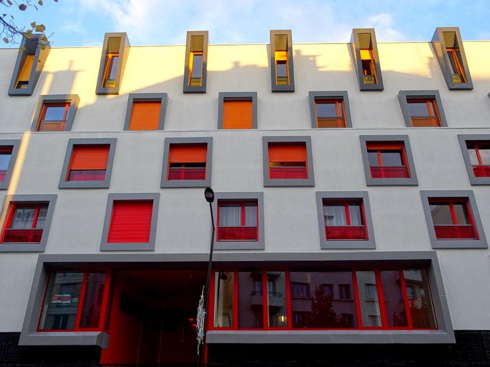 Immeuble aux fenêtres jaunes, oranges et rouges, au 99 rue… 