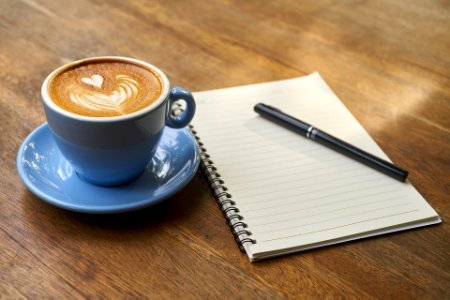 Coffee with Notebook on table in office photo