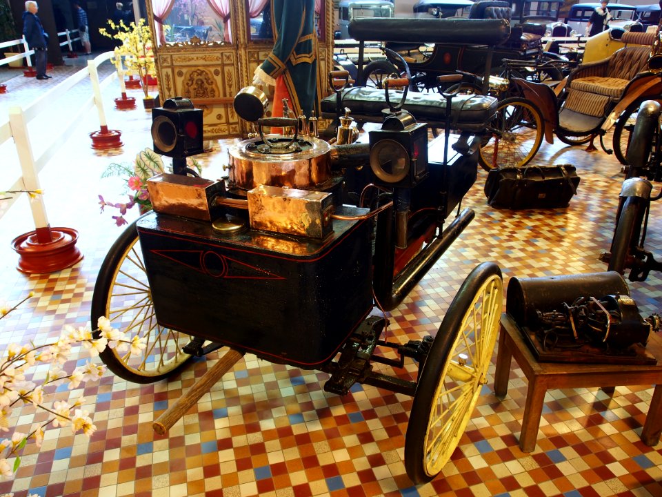 1885_De_Dion_Bouton_tricycle_with_front_mounted_boiler_and_water_tank_and_coal_chest_on_each_side_of_rear_wheel_at_the_Musée_Automobile_de_Vendée_pic-3