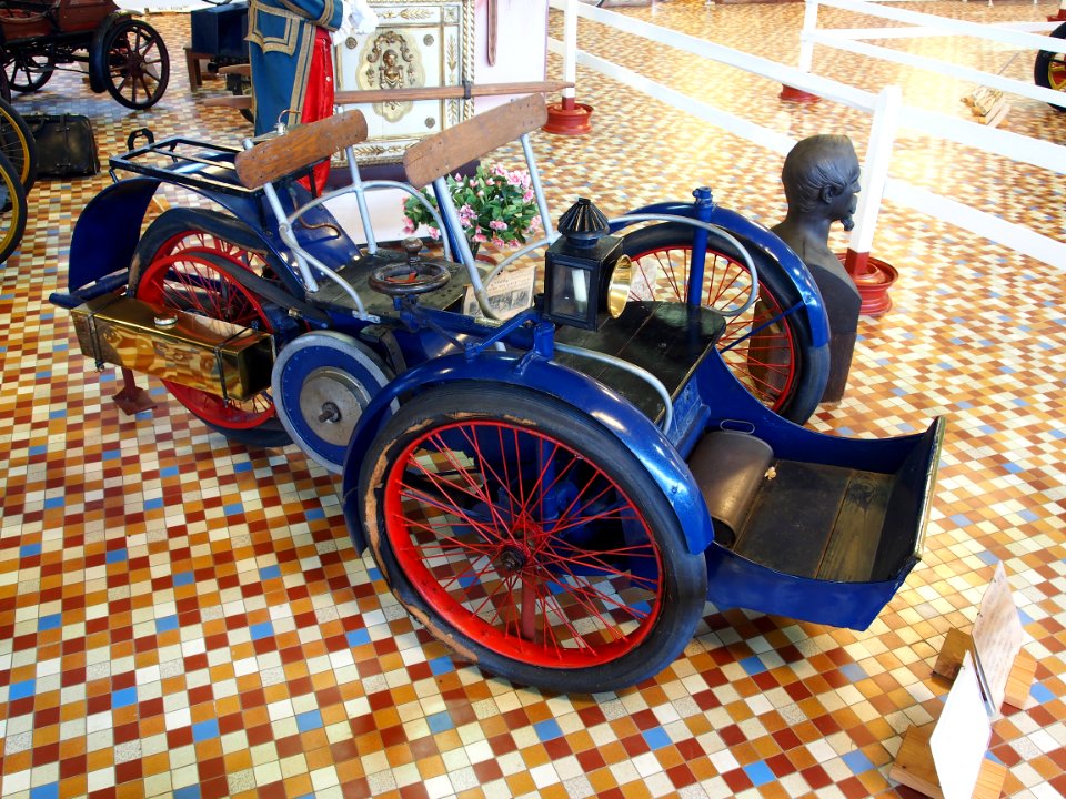 1898_Léon_Bollée_tricycle_car,_single_horizontal_cylinder,_burner_ignition_and_flat_belt_transmission_at_the_Musée_Automobile_de_Vendée_pic-1