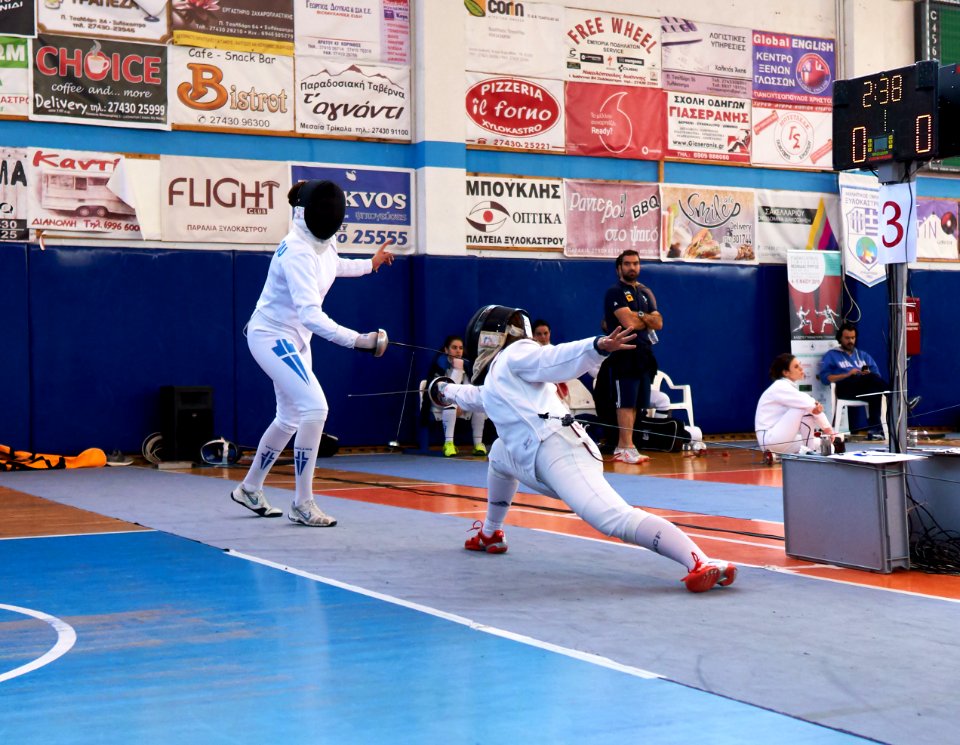 2nd_Leonidas_Pirgos_Fencing_Tournament._The_fencer_on_the_right_lunges_the_parry_of_her_opponent_and_goes_straight_for_a_foot_touch