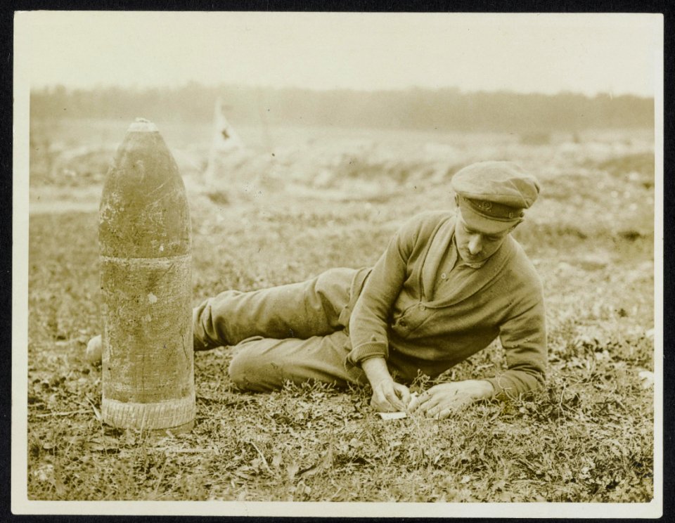 A_letter_home._Unexploded_Boche_shell_beside_the_writer,_Bestanddeelnr_158-0885