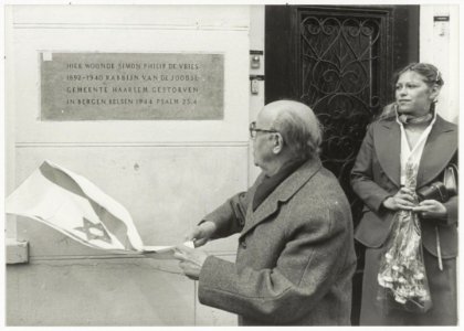 Aäron_de_Vries,_68-jarige_zoon_van_de_omgekomen_rabbijn_Simon_Philip_de_Vries,_onthult_een_gedenkplaat_aan_de_gevel_van_de_vroegere_woning_van_zijn_vader_aan_de_Bakenessergracht_46A._NL-HlmNHA_54011368