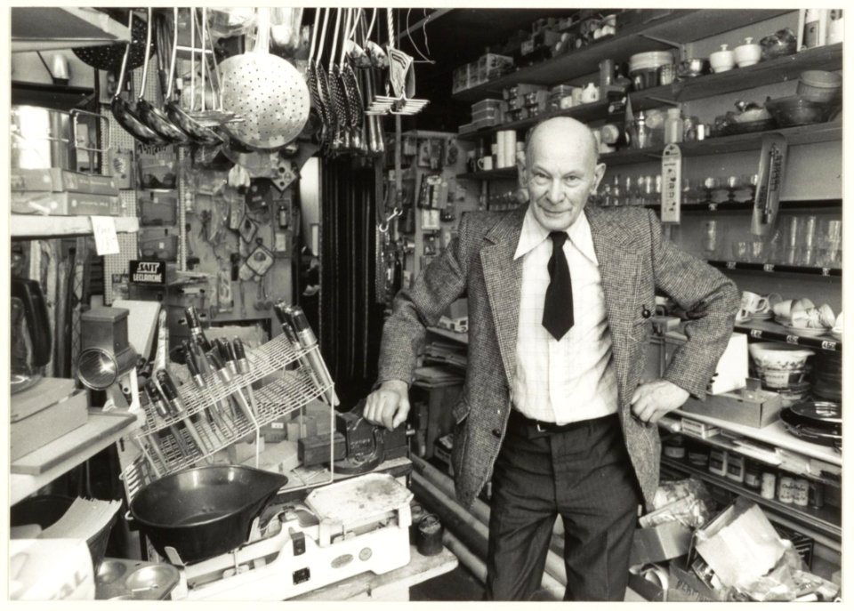 80-jarige_winkelier_'Winkel_van_Sinkel',_Giljam_Lokerse._Van_Ostadestraat_7._NL-HlmNHA_54015274