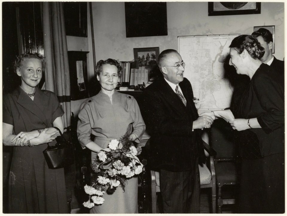 Afscheid_van_A.C._Sandijck._Archivaris_mevrouw_Kurtz_overhandigt_een_geschenk._Links_en_rechts_de_heer_en_mevrouw_Groen._NL-HlmNHA_54001235