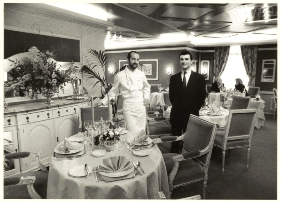 Afgebeeld_is_het_interieur_van_het_restaurant_De_Oude_Geleerde_Man_aan_de_Rijksstraatweg_51_te_Bennebroek._Mede_afgebeeld_zijn_waarschijnlijk_de_eigenaar_en_de_chef-kok._NL-HlmNHA_54023663
