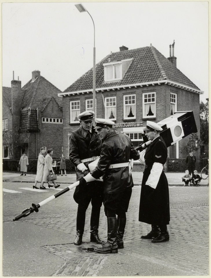 Agenten_plaatsen_een_verplaatsbaar_verkeersbord._NL-HlmNHA_54004164