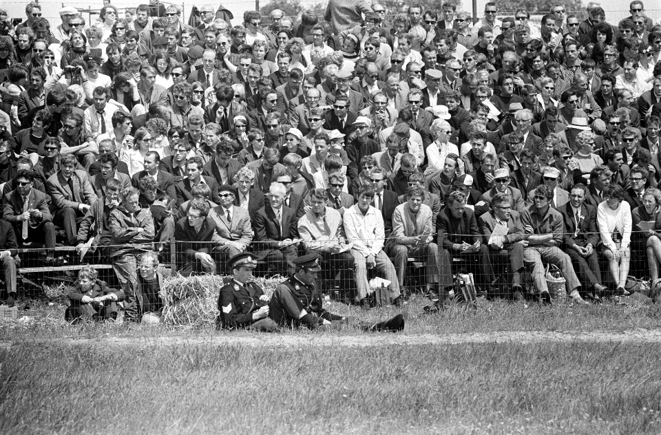 Agenten_zitten_voor_het_publiek_in_het_gras_langs_de_baan,_Bestanddeelnr_922-5820
