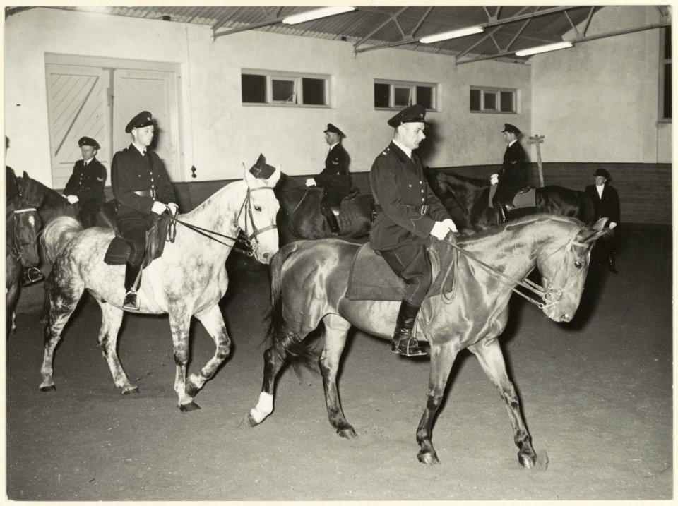 Agenten_te_paard_tijdens_de_training_in_de_manege_aan_de_Wagenweg._NL-HlmNHA_54004165