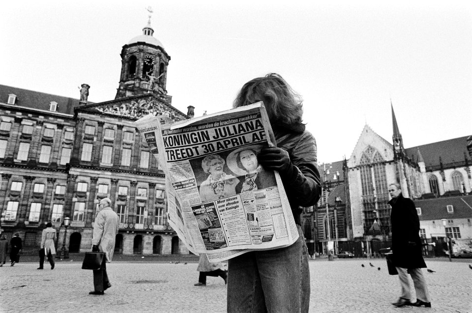 Aftreden_Koningin_Juliana_meisje_leest_ochtendkrant_met_grote_kop_op_de_Dam,_l,_Bestanddeelnr_930-6516