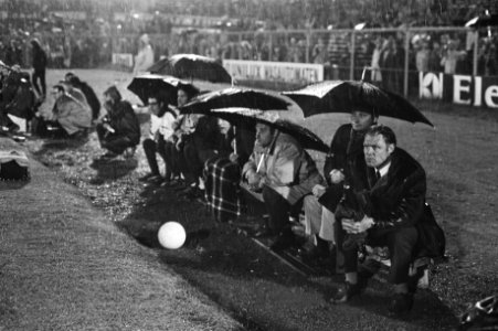Ajax-Feyenoord 1-3. Spelers met paraplu's op de reservebank, rechts Ajax-traine…, Bestanddeelnr 924-5913