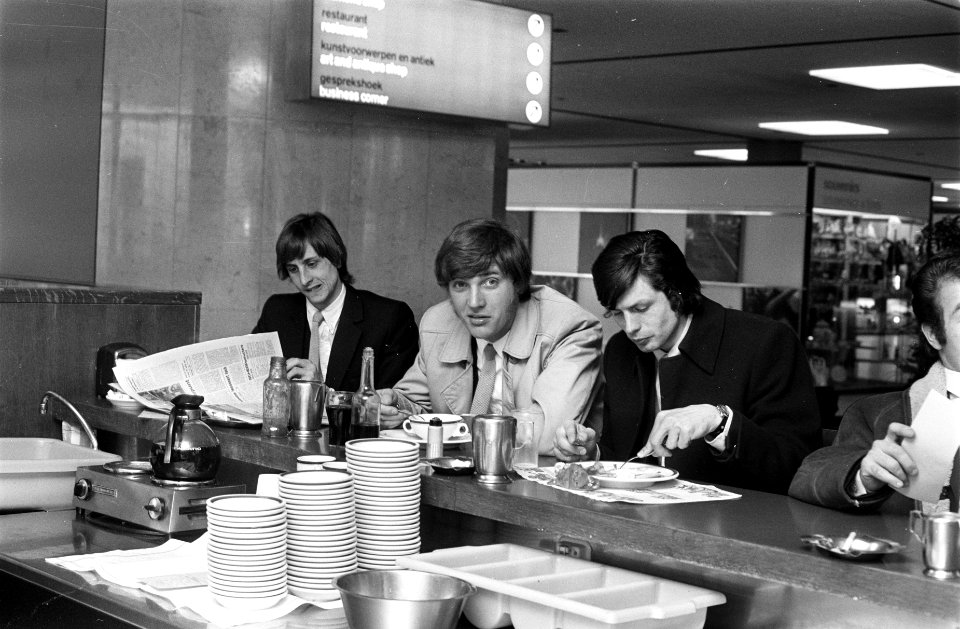 Ajax-elftal vertrekt naar Londen vanaf Schiphol. Cruijff, Krol en Suurbier eten , Bestanddeelnr 923-4094