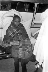 Aankomst van 5 kinderen uit Biafra op Schiphol een van de jongens dik in deken g, Bestanddeelnr 921-7495