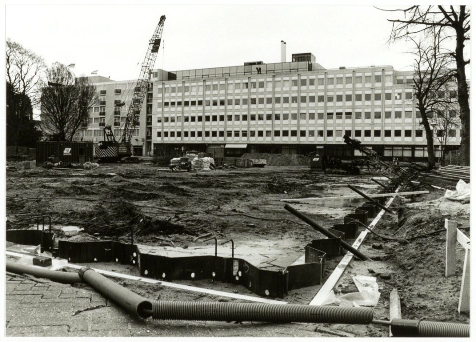 Aanbrengen van stalen damwanden t.b.v. de bouwput voor de parkeergarage aan het Houtplein, ziende naar het westen, met op de achtergrond de achterzijde van het kantoorgebouw van de Provincie, NL-HlmNHA 54035302
