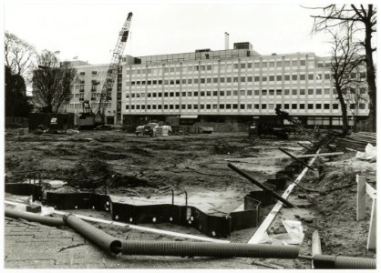 Aanbrengen van stalen damwanden t.b.v. de bouwput voor de parkeergarage aan het Houtplein, ziende naar het westen, met op de achtergrond de achterzijde van het kantoorgebouw van de Provincie, NL-HlmNHA 54035302