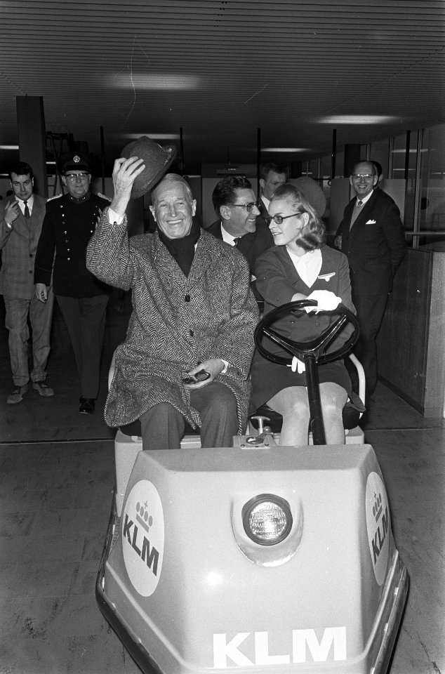 Aankomst Maurice Chevalier op Schiphol, hier met stewardess op karretje, Bestanddeelnr 921-0561