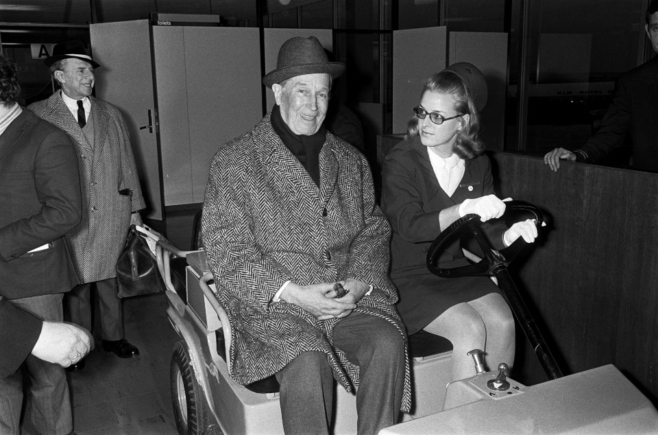 Aankomst Maurice Chevalier op Schiphol, hier met stewardess op karretje, Bestanddeelnr 921-0564