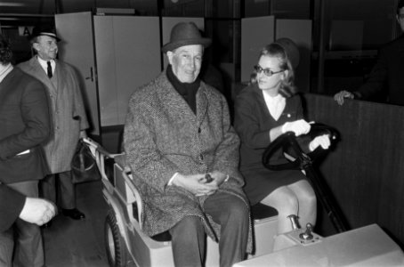 Aankomst Maurice Chevalier op Schiphol, hier met stewardess op karretje, Bestanddeelnr 921-0564