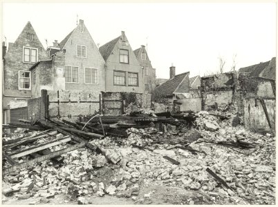 Achtergevels Groot Heiligland 21-19-17-15. Op de voorgrond een slooppand aan de Zonnesteeg, dat vermoedelijk als gevolg van brandstichting tot de grond toe is afgebrand. NL-HlmNHA 54012319