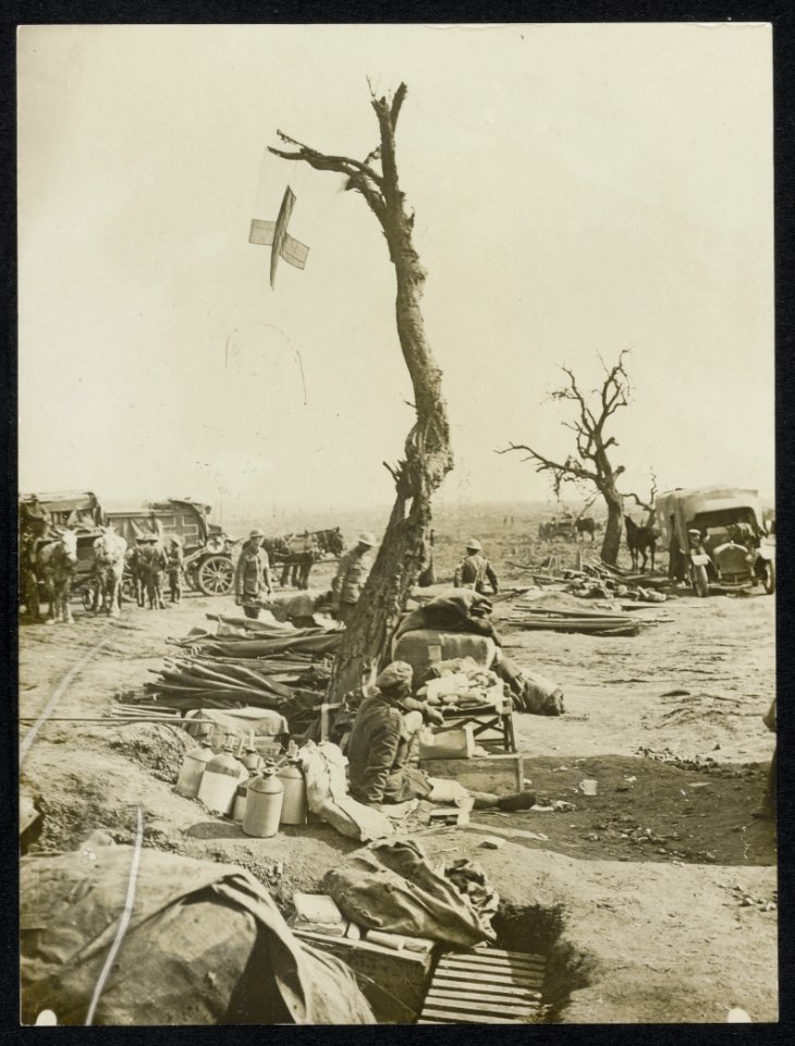 An advanced dressing station. A Red Cross flag is affixed to a tree, Bestanddeelnr 158-1018