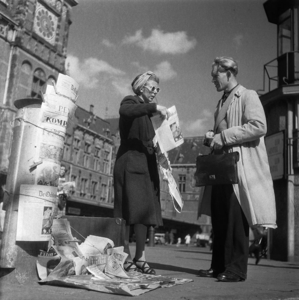 Amsterdam. Een krantenverkoopster voor het Centraal Station met een klant, Bestanddeelnr 901-8136